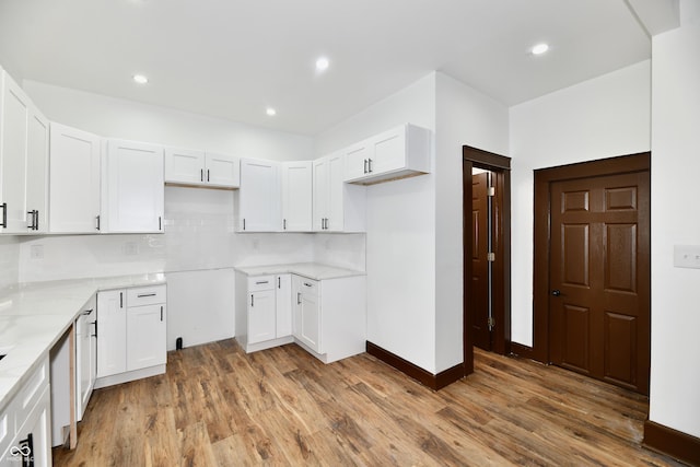 kitchen featuring white cabinetry, hardwood / wood-style floors, light stone counters, and backsplash