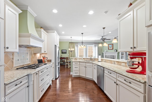 kitchen featuring premium range hood, appliances with stainless steel finishes, hanging light fixtures, white cabinets, and kitchen peninsula