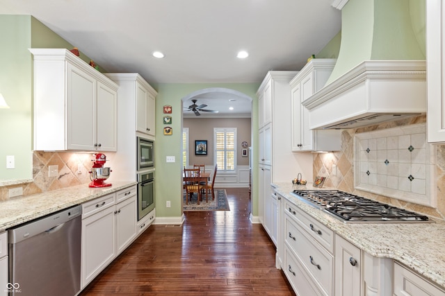 kitchen featuring custom exhaust hood, white cabinetry, light stone countertops, and stainless steel appliances