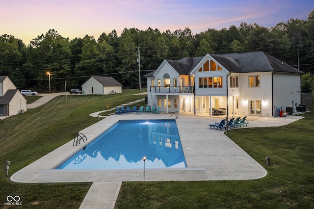 pool at dusk with a lawn and a patio