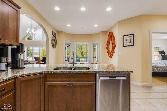 kitchen featuring sink, light stone counters, light tile patterned floors, dishwasher, and a notable chandelier