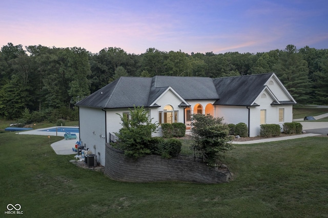 view of front of house with central AC and a yard