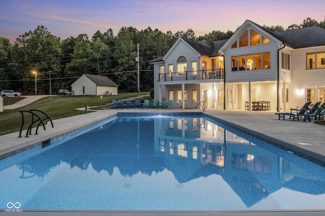 pool at dusk with a yard and a patio area