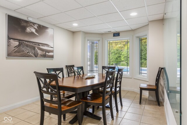 dining area with a drop ceiling and light tile patterned floors