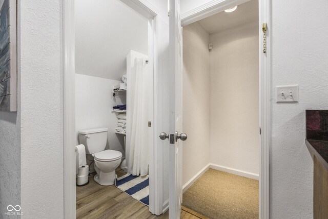 bathroom with hardwood / wood-style flooring, vaulted ceiling, and toilet