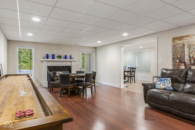 dining area with a premium fireplace, dark hardwood / wood-style floors, and a paneled ceiling