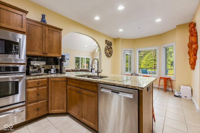 kitchen featuring sink, a wealth of natural light, stainless steel appliances, and light stone countertops