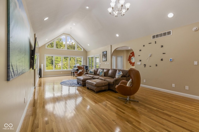 living room featuring an inviting chandelier, high vaulted ceiling, and light hardwood / wood-style floors