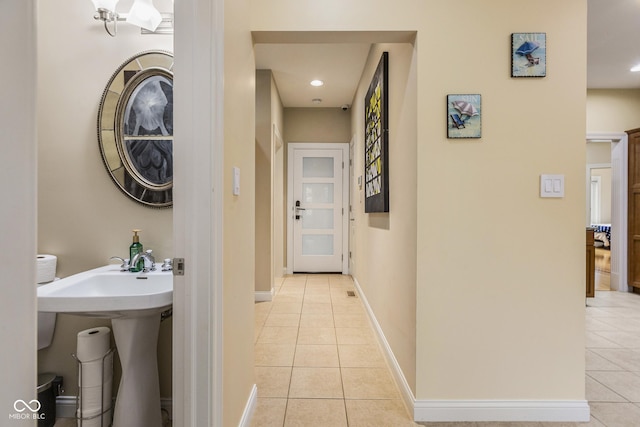 hall featuring sink and light tile patterned flooring