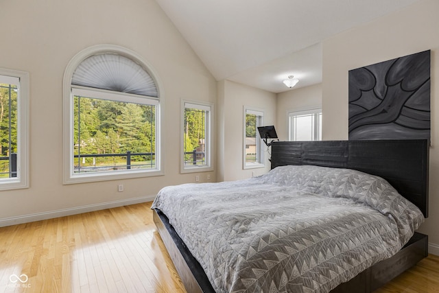 bedroom featuring vaulted ceiling, multiple windows, and light wood-type flooring