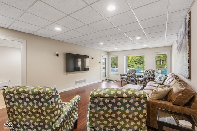 living room with dark hardwood / wood-style flooring and a paneled ceiling