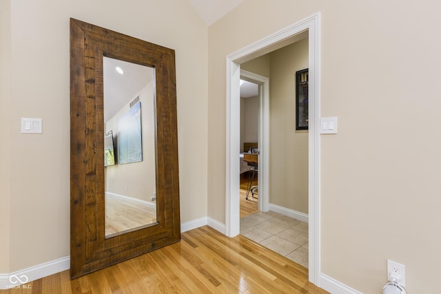 hallway featuring lofted ceiling and light wood-type flooring