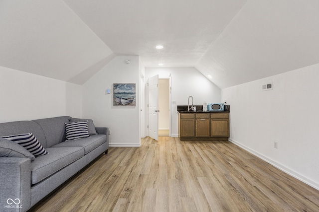 living room with vaulted ceiling, sink, and light hardwood / wood-style flooring