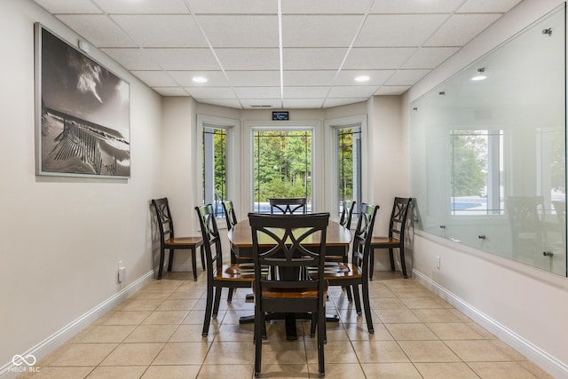 tiled dining space featuring a drop ceiling