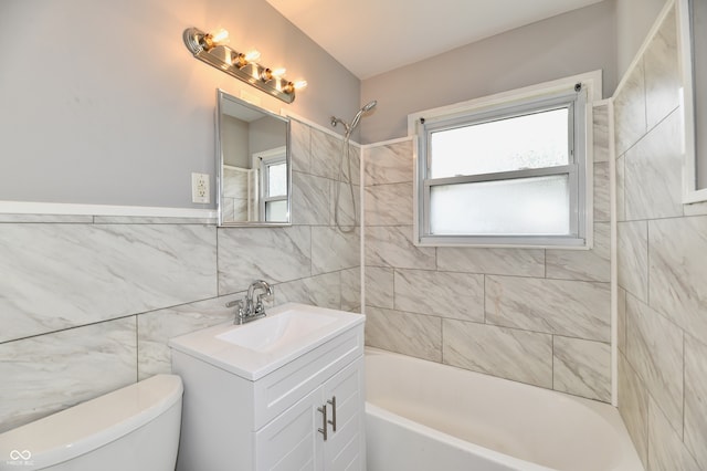 full bathroom with vanity, tile walls, toilet, and a healthy amount of sunlight