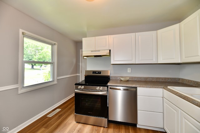 kitchen featuring appliances with stainless steel finishes, light hardwood / wood-style flooring, white cabinets, and sink