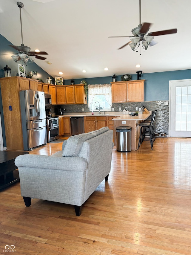 living room with recessed lighting, vaulted ceiling, and light wood-style flooring