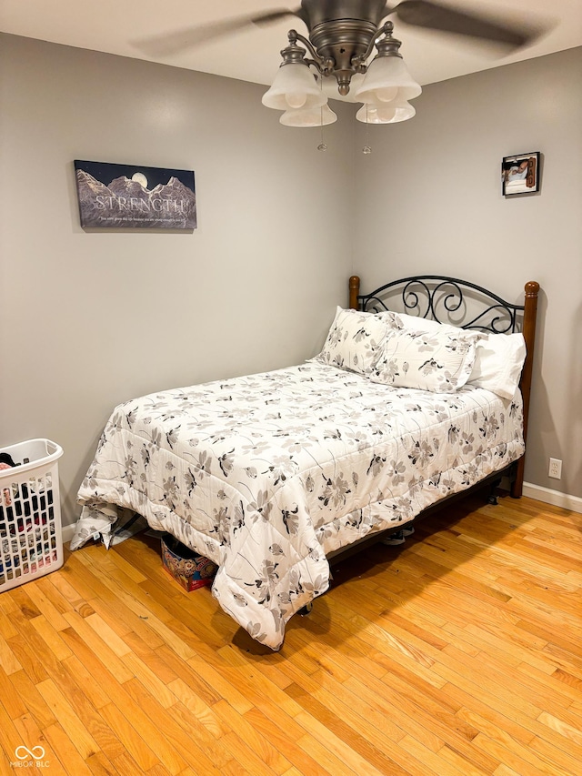 bedroom with a ceiling fan, baseboards, and wood finished floors