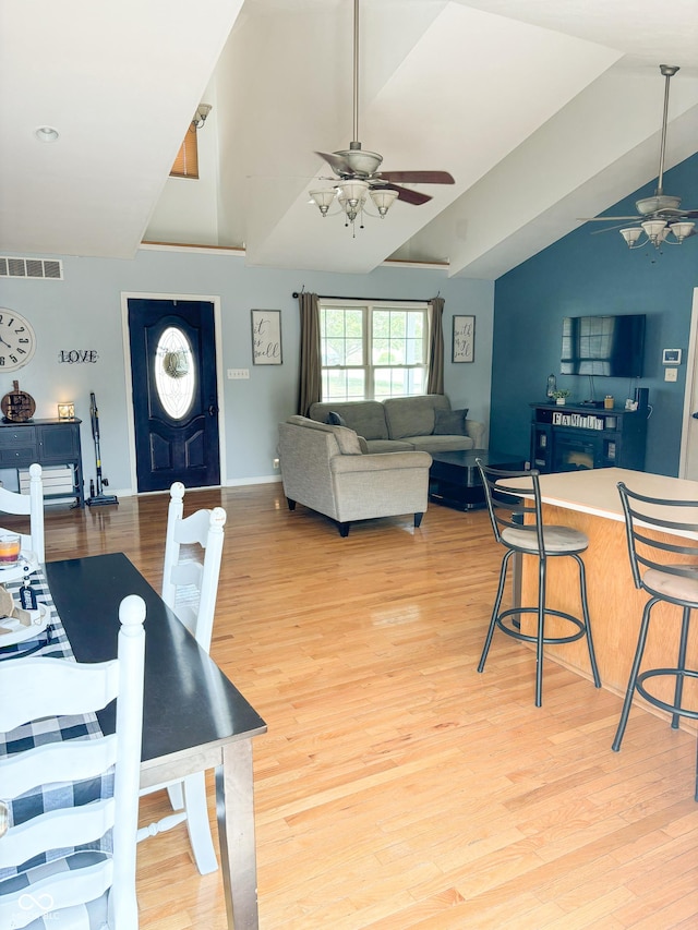 dining area with lofted ceiling, visible vents, a ceiling fan, light wood-style floors, and baseboards