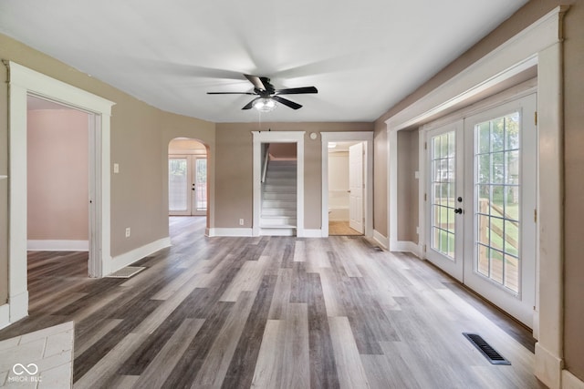 unfurnished living room with hardwood / wood-style flooring, ceiling fan, and french doors