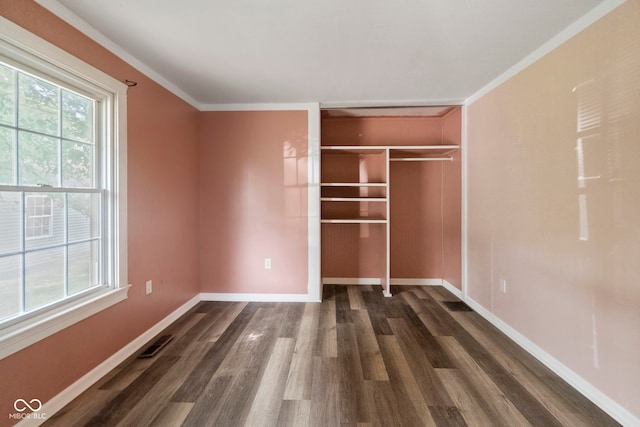 unfurnished bedroom with dark wood-type flooring, crown molding, and a closet