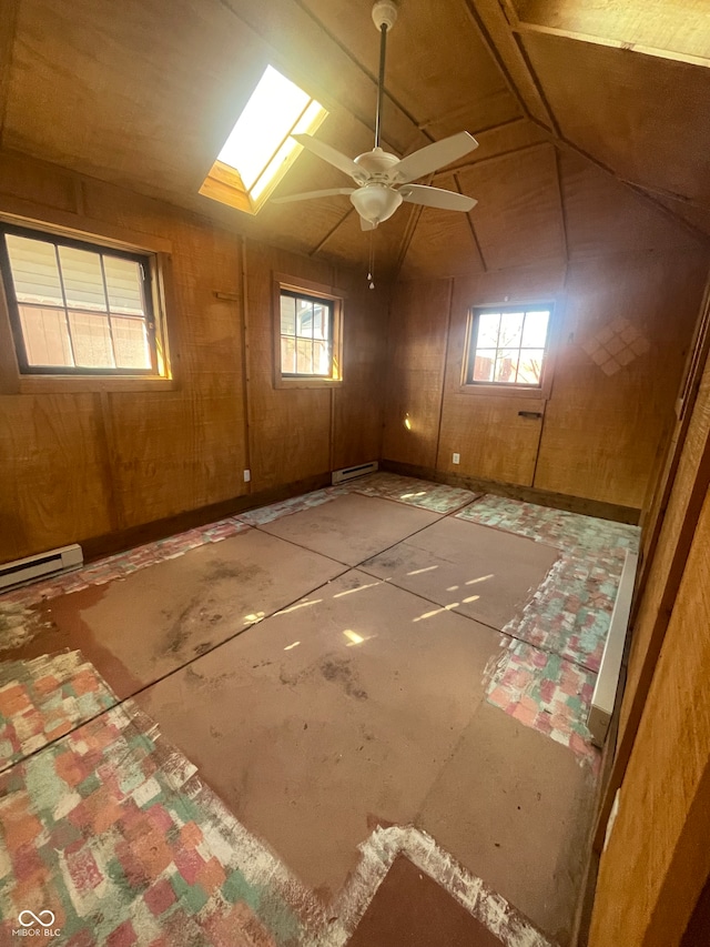 empty room with lofted ceiling with skylight, ceiling fan, a baseboard heating unit, and wood walls