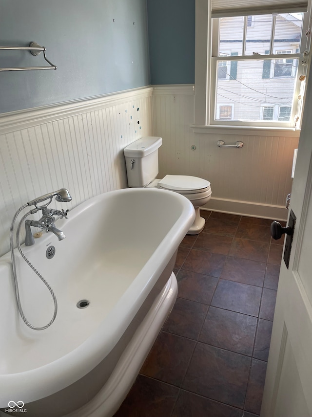 bathroom featuring tile patterned flooring, toilet, and a tub