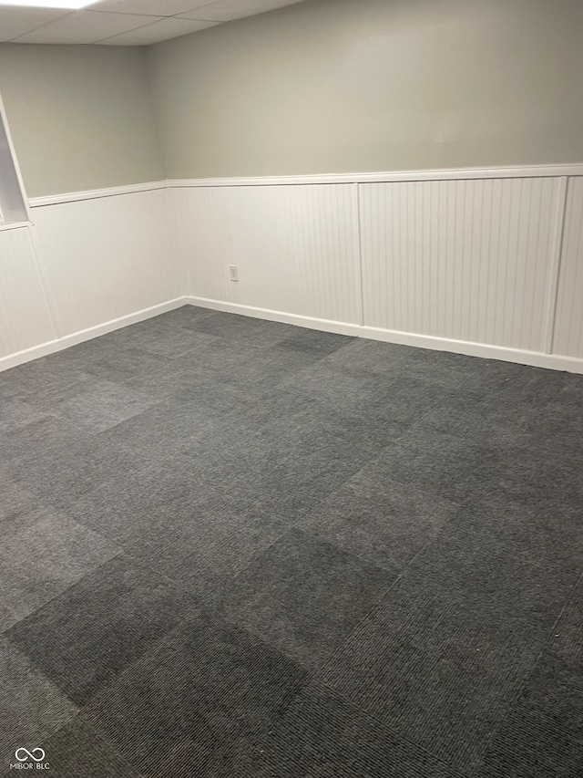 empty room with a paneled ceiling and dark carpet