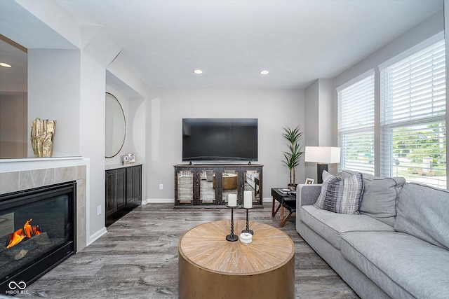 living room with a tile fireplace, recessed lighting, baseboards, and wood finished floors