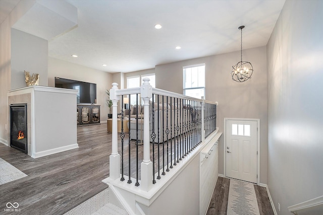 stairs featuring a lit fireplace, baseboards, and wood finished floors