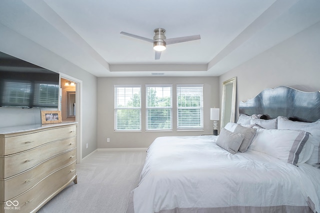 bedroom featuring light colored carpet, a tray ceiling, and ceiling fan