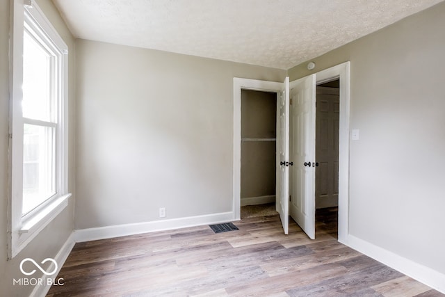 unfurnished bedroom with a textured ceiling and light wood-type flooring