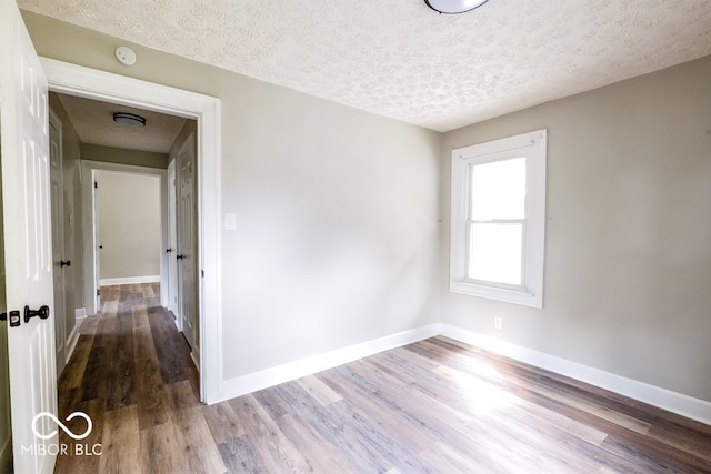 empty room featuring a textured ceiling and hardwood / wood-style flooring