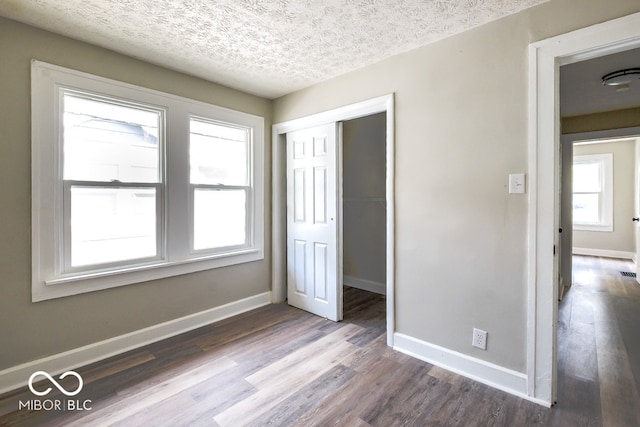 unfurnished bedroom with a closet, wood-type flooring, and a textured ceiling