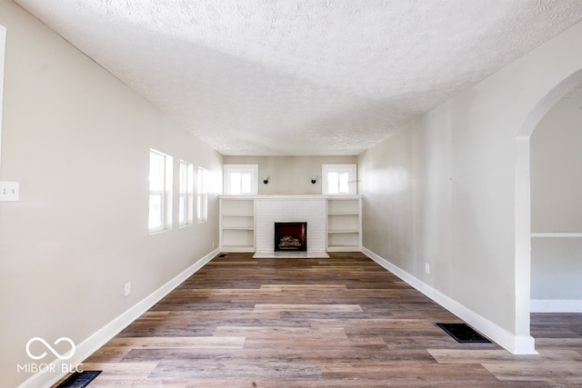 unfurnished living room with a textured ceiling, a fireplace, and wood-type flooring