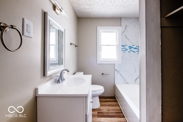 bathroom featuring vanity, toilet, hardwood / wood-style flooring, and a textured ceiling