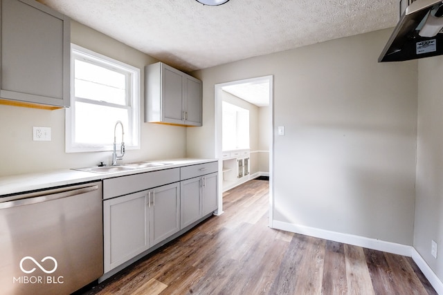 kitchen featuring hardwood / wood-style flooring, sink, gray cabinets, stainless steel dishwasher, and a textured ceiling