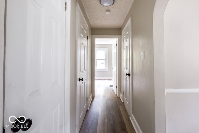 corridor featuring a textured ceiling and dark wood-type flooring