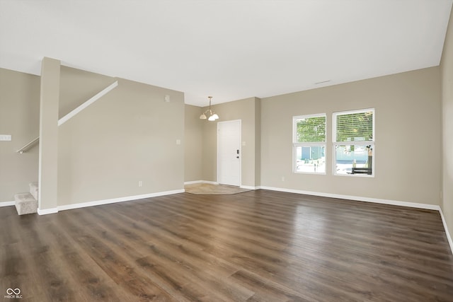 spare room featuring dark wood-type flooring and a notable chandelier