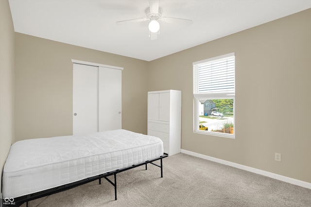 carpeted bedroom with ceiling fan and a closet