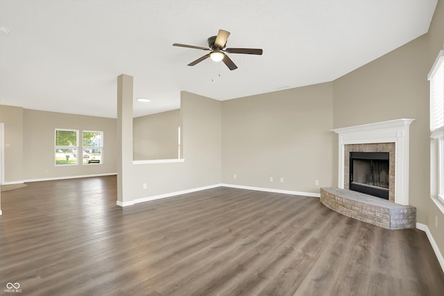 unfurnished living room featuring ceiling fan, a brick fireplace, and dark hardwood / wood-style flooring