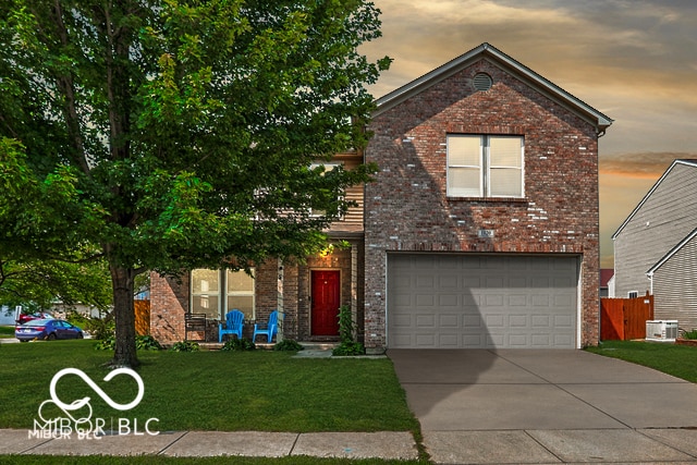 view of front property featuring a yard, a garage, and central AC