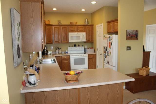 kitchen with sink, white appliances, and kitchen peninsula