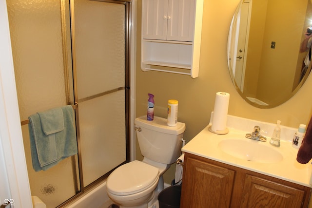 bathroom featuring vanity, a shower with shower door, and toilet