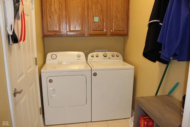 clothes washing area with cabinets, washing machine and dryer, and light tile patterned floors