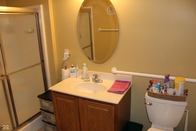 bathroom featuring vanity, a shower with shower door, and toilet