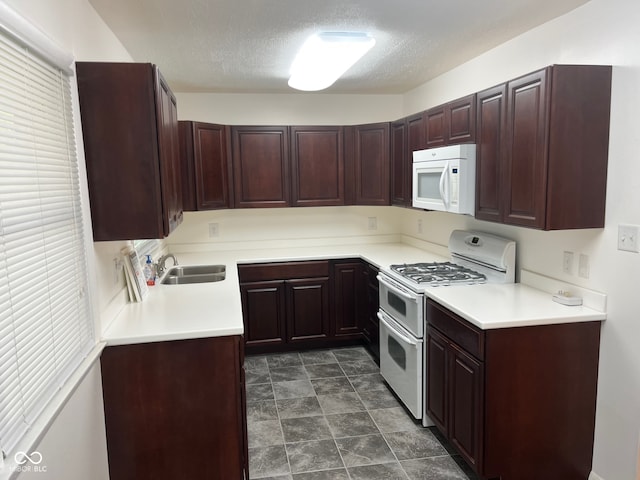 kitchen featuring sink, dark tile patterned floors, a textured ceiling, and white appliances