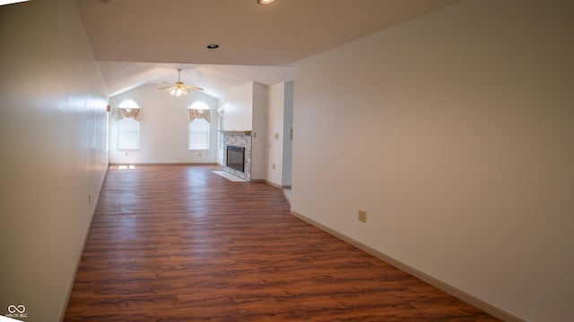 unfurnished living room featuring baseboards, a ceiling fan, a fireplace with flush hearth, dark wood-style flooring, and vaulted ceiling