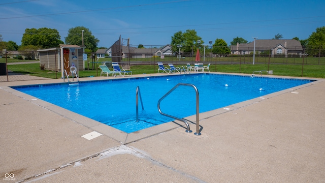 view of pool with a lawn and an outdoor structure