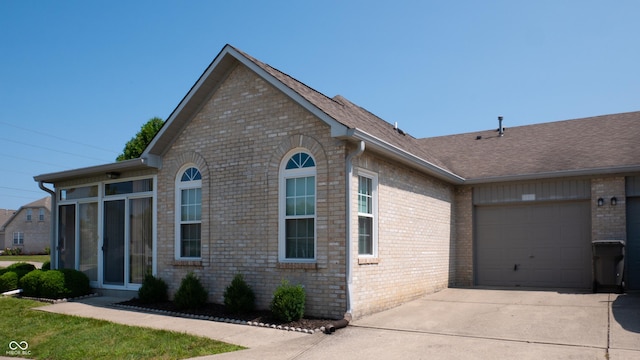 view of front facade featuring brick siding, driveway, an attached garage, and roof with shingles